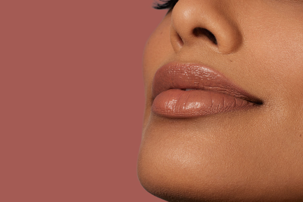 a woman's part of face - nose and lips on a pink background