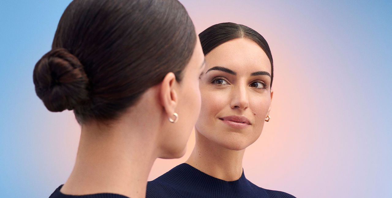 Woman staring back at herself in a mirror smiling